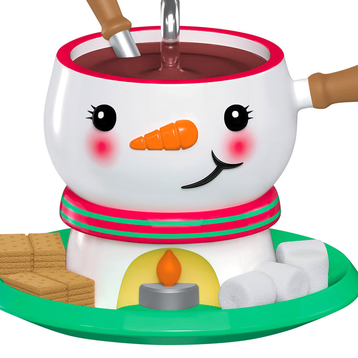 Snowman-themed hot chocolate mug with a carrot nose and candy cane scarf, filled with hot chocolate.