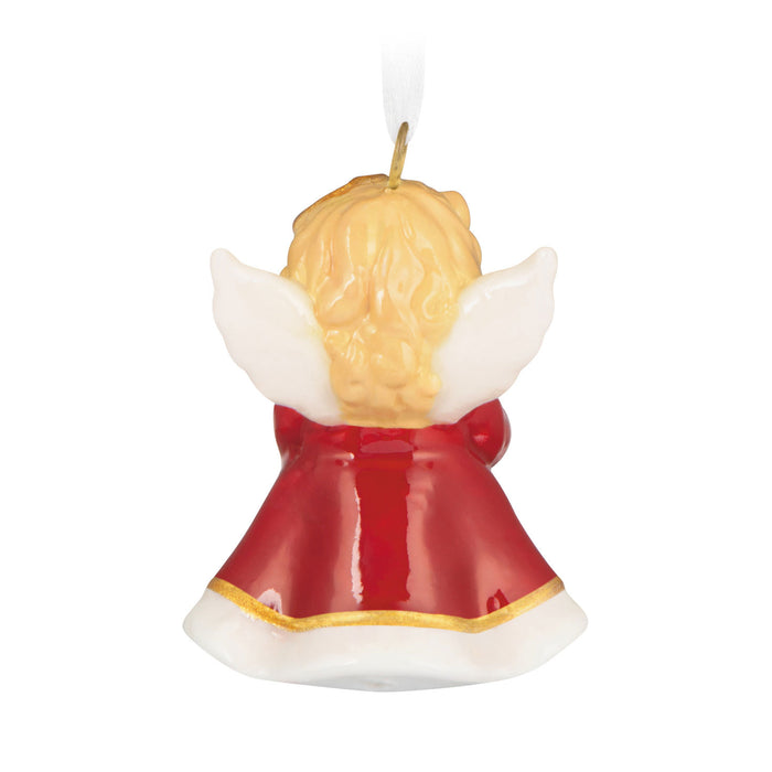 Angel-shaped candle with red dress and white wings on a white background