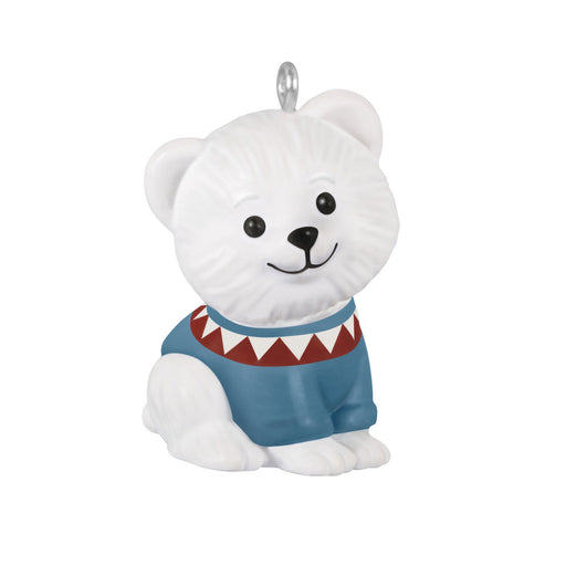 White polar bear ornament wearing a blue sweater with a red and white pattern on a white background