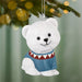 White polar bear ornament with a blue sweater hanging on a Christmas tree.