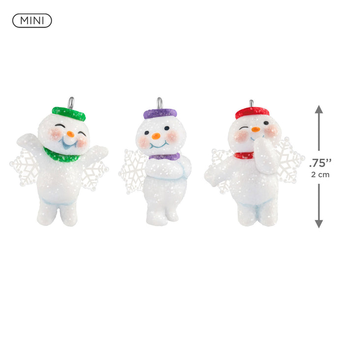 Three small snowman figurines with colorful hats on a white background