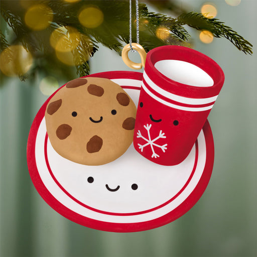 Christmas ornament with a cookie, cup, and saucer on a tree branch.