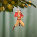 Character ornament hanging on a Christmas tree branch with blurred lights in the background