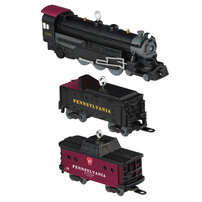 Model train set with black locomotive and two red and black passenger cars on a white background