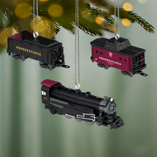 Three Pennsylvania Railroad train ornaments hanging on a Christmas tree.