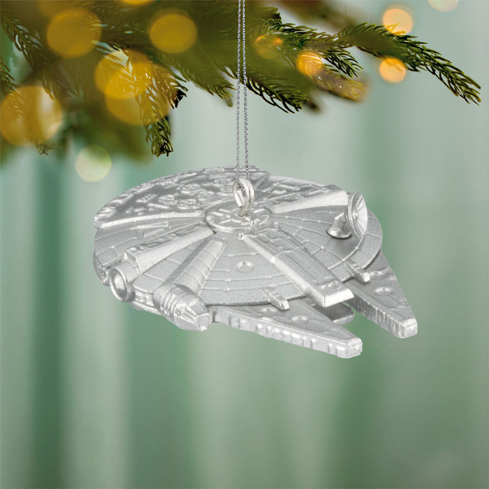 Starship ornament hanging on a Christmas tree with blurred lights in the background