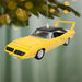 Yellow car ornament hanging on a Christmas tree with a green background