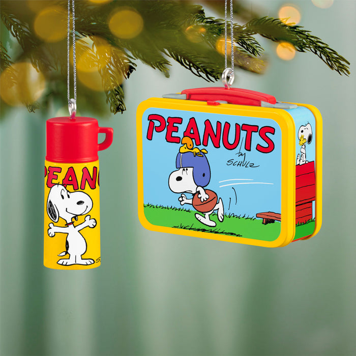 Peanuts-themed lunch box and thermos hanging from a Christmas tree.