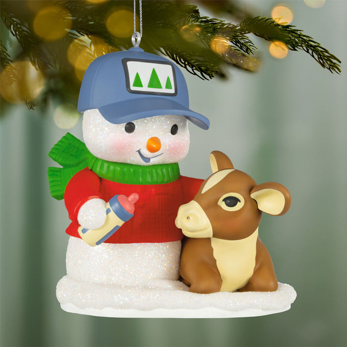 Decorative ornament of a snowman with a calf and baby bottle, hanging on a Christmas tree.