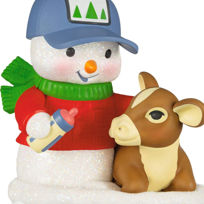 Snowman with a blue cap and red sweater holding a bottle, standing next to a calf on a white background