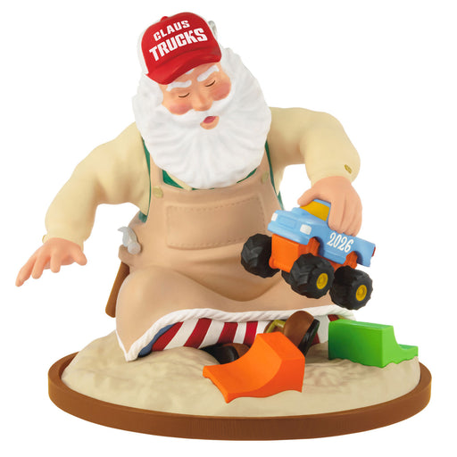 Figurine of Santa Claus in an apron and red cap with a toy truck, on a white background