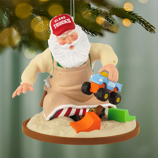 Decorative ornament of Santa Claus with a toy truck and apron, hanging on a Christmas tree.
