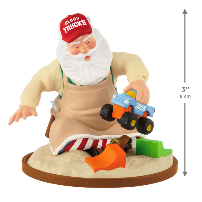 Toy figure of Santa Claus wearing a 'Claus Trucks' hat with a toy truck and tools on a white background.