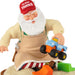 Toy figure of Santa Claus in overalls holding a toy truck with 'Claus Trucks' branding.