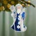 Decorative ornament of a character in blue and white attire with a staff, hanging against a blurred green background.