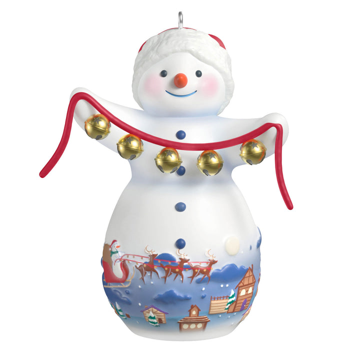 Decorative snowman ornament with jingle bells and a Santa Claus scene on a white background