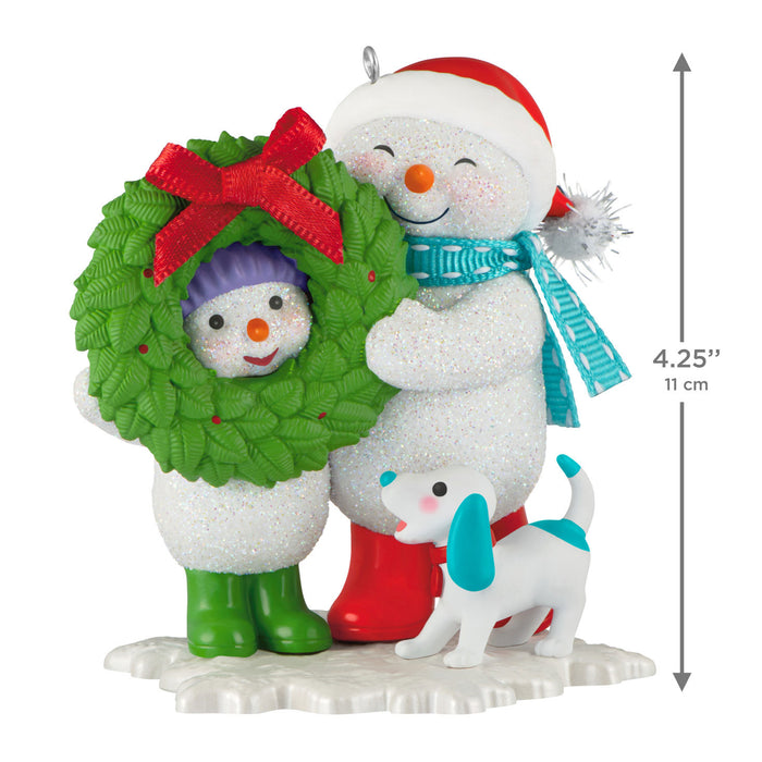 Decorative Christmas ornament featuring two snowmen with a dog and a wreath, with a measurement indicator.