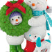 Two Christmas-themed figurines, one resembling a snowman in a wreath and the other with a dog, on a white background.