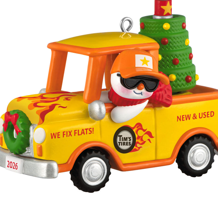 Christmas ornament of a snowman driver in a yellow truck with festive decorations on a white background