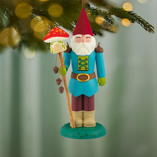 Colorful gnome ornament with a mushroom staff hanging from a tree.