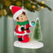 Christmas ornament of a elf in a Santa outfit with a small tree and a little red feathered bird, hanging from a tree.