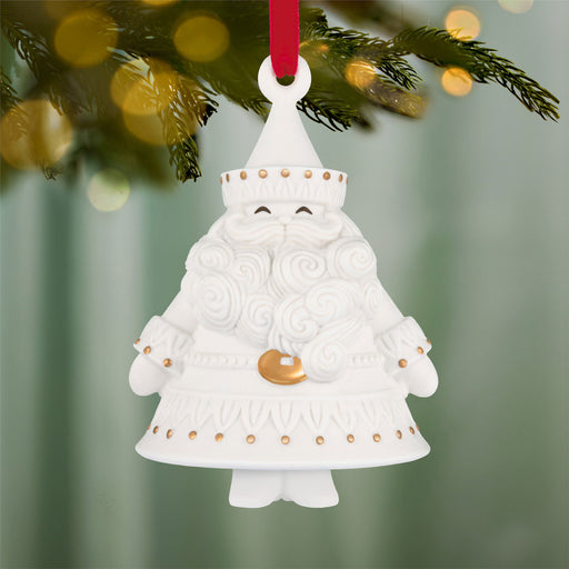 White ceramic Santa Claus ornament with gold details hanging from a tree.