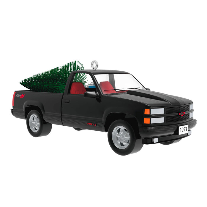 Black truck ornament with a Christmas tree in the bed on a white background