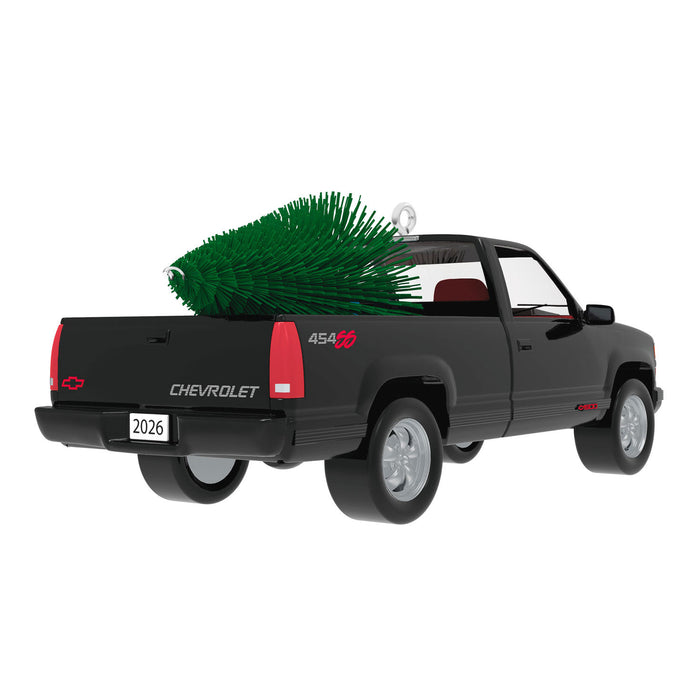 Model of a black Chevrolet truck with a Christmas tree in the bed on a white background