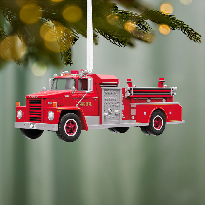 Red fire truck ornament hanging on a Christmas tree with a green background