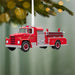 Red fire truck ornament hanging on a Christmas tree with a green background