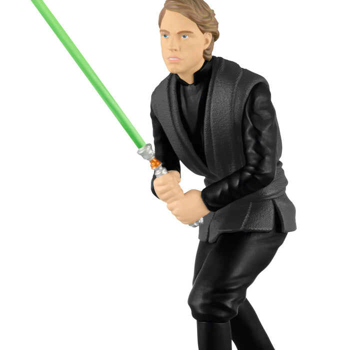 Action figure in black outfit holding a green lightsaber on a white background