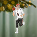 Football player ornament with helmet and jersey, hanging on a Christmas tree.