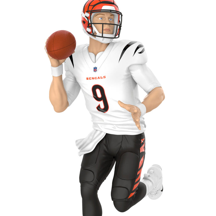 Football player figurine in a white uniform with black pants, holding a football, on a white background.