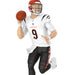 Football player figurine in a white uniform with black pants, holding a football, on a white background.