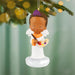 Decorative angel ornament with a child holding a paintbrush and palette, hanging on a Christmas tree.