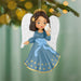 Angel ornament with blue dress and white wings holding a dove, hanging from a tree.