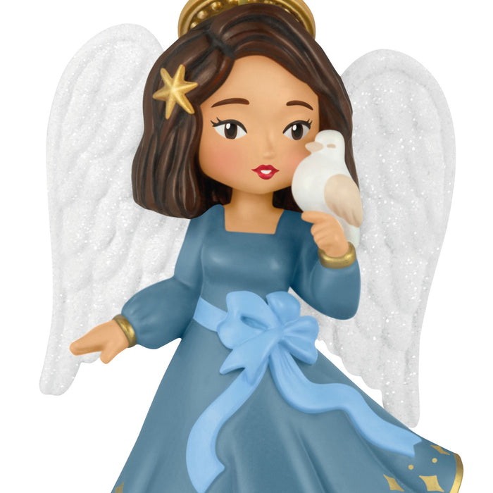 Angel figurine with white wings, blue dress, and holding a dove on a white background