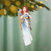 Decorative angel ornament with red hair hanging on a Christmas tree.
