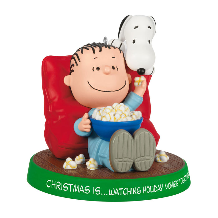 Figurine of a character watching TV with a bowl of popcorn, sitting on a red chair, with Snoopy on their head, on a white background.