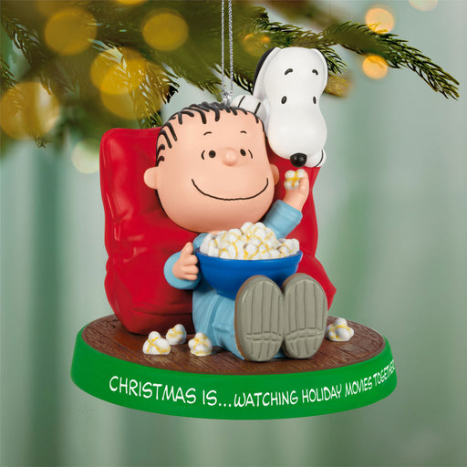 Christmas ornament featuring a character sitting in a chair with a bowl of popcorn, surrounded by festive lights.