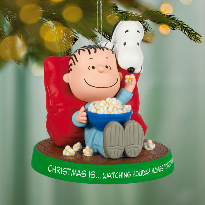 Christmas ornament featuring a character sitting in a chair with a bowl of popcorn, surrounded by festive lights.