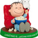 Ornament featuring a character from Peanuts sitting on a red chair with popcorn, next to a dog, on a white background.