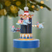 Decorative Christmas ornament with cartoon elephants on a carousel against a blurred green background