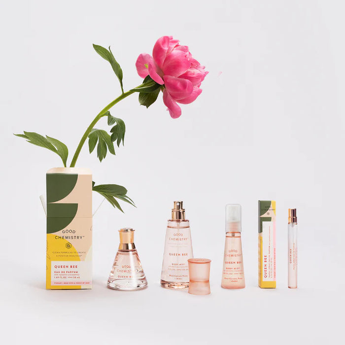 Collection of perfume bottles and packaging with a pink flower on a light gray background