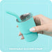 Turquoise tumbler with a removable silicone straw held by a hand against a light blue background.