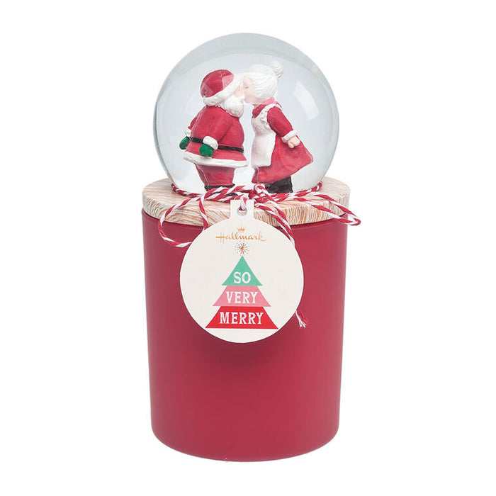 Red candle with a snow globe featuring Santa Claus on top, against a white background