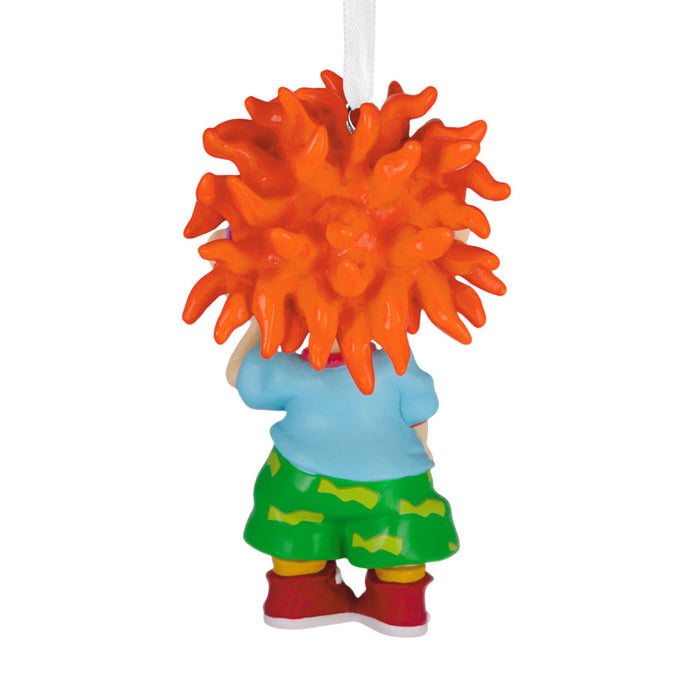 A small hanging ornament shaped like a child seen from the back, with a large bright orange spiky hairpiece, light blue top, green shorts with yellow stripes, red shoes, and a white hanging ribbon on a plain white background.