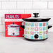 Slow cooker with Peanuts character design next to its packaging on a white tiled wall background