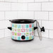 Small slow cooker with colorful design on a white surface against a tiled wall.