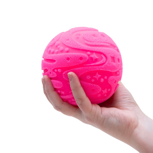 Pink textured ball held in a hand against a white background